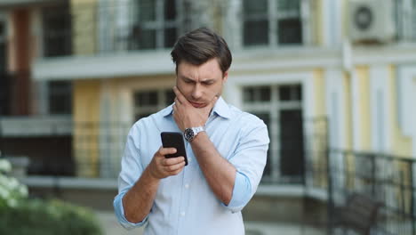 portrait man typing on phone at street. businessman using smartphone outdoors