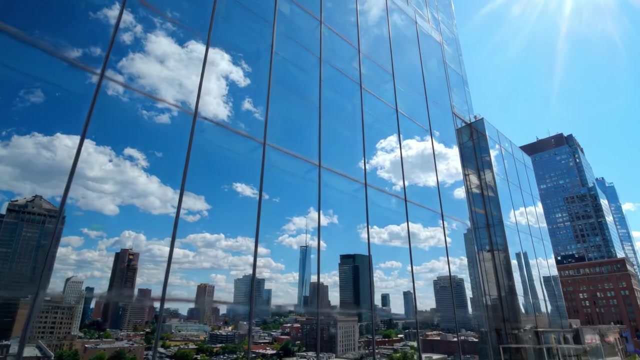 Arquitectura Bancaria Moderna: Un Vistazo a una Institución Financiera con Impresionantes Fachadas de Cristal Reflejando Rascacielos Urbanos Bajo un Cielo Azul Claro