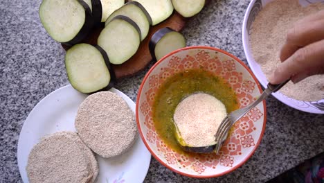 Dipping-Breaded-Slice-Of-Eggplant-Into-Seasoned-Egg-In-A-Bowl