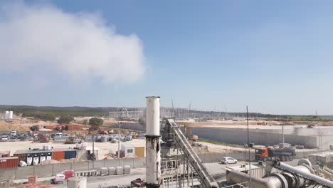 chimney emitting smoke in an industrial area under construction