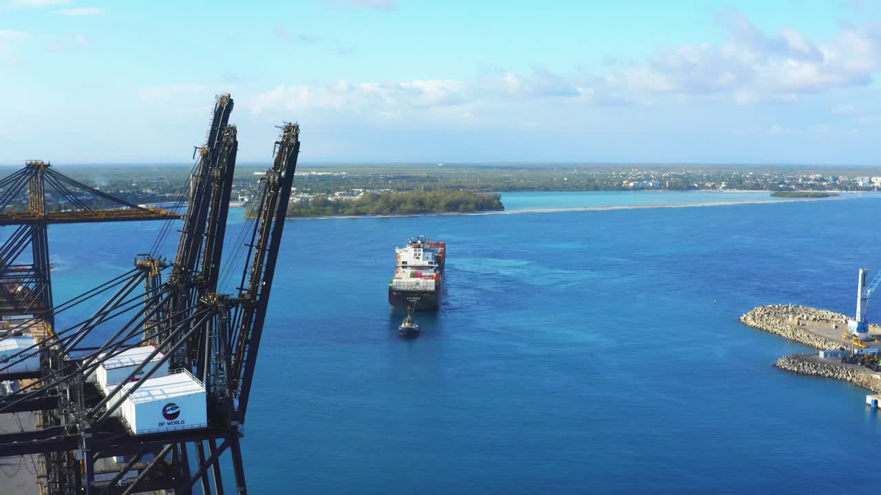 emocionante vuelo que se acerca a las grúas portuarias sobre el agua azul del océano hacia el buque de carga tirado por un remolcador, punta caucedo, república dominicana, antena aérea hacia adelante