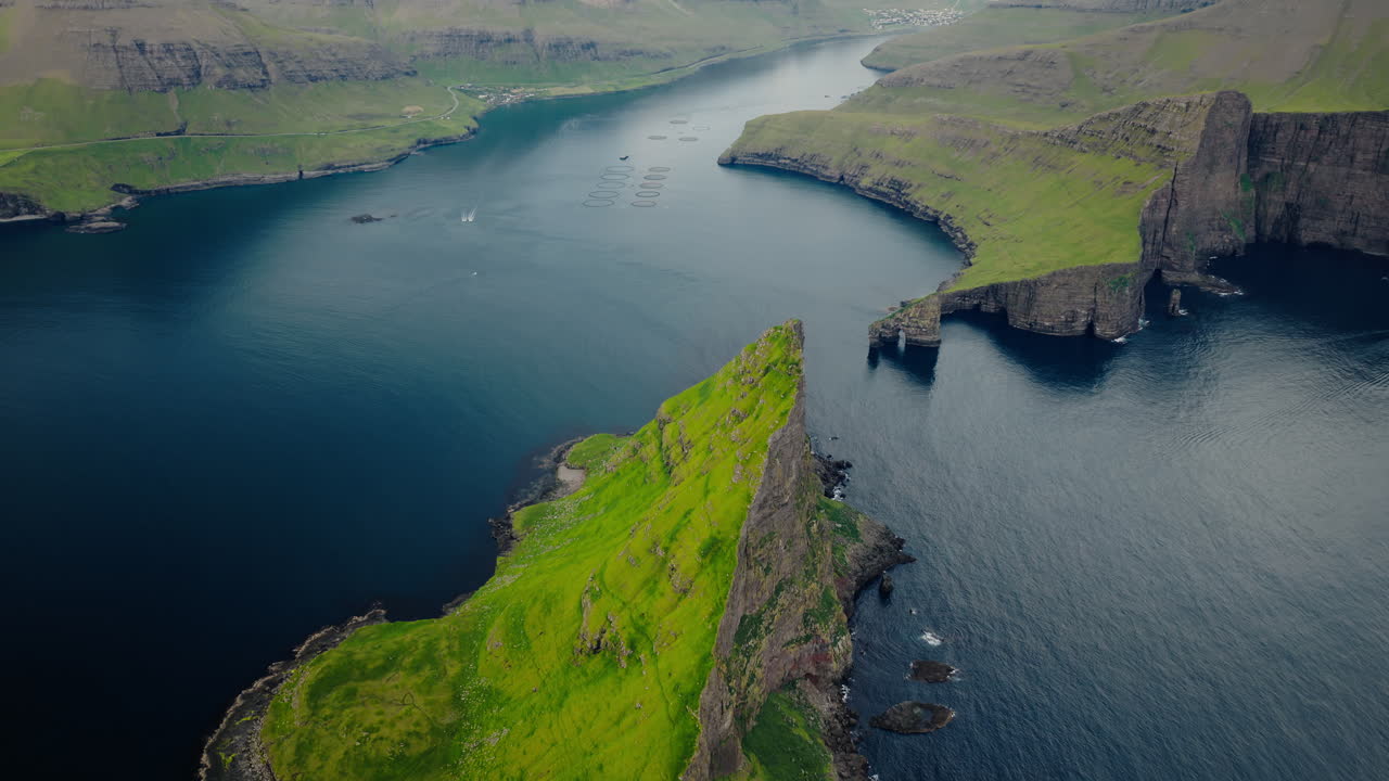 Aerial View of Dramatic Green Cliffs and Ocean Landscape with Aquaculture Pens