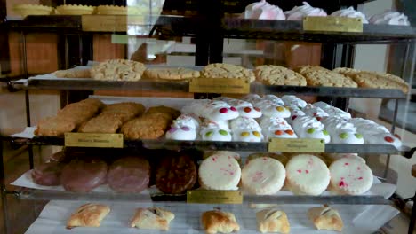 a bakery display case filled with various cookies and pastries in a well-lit shop environment