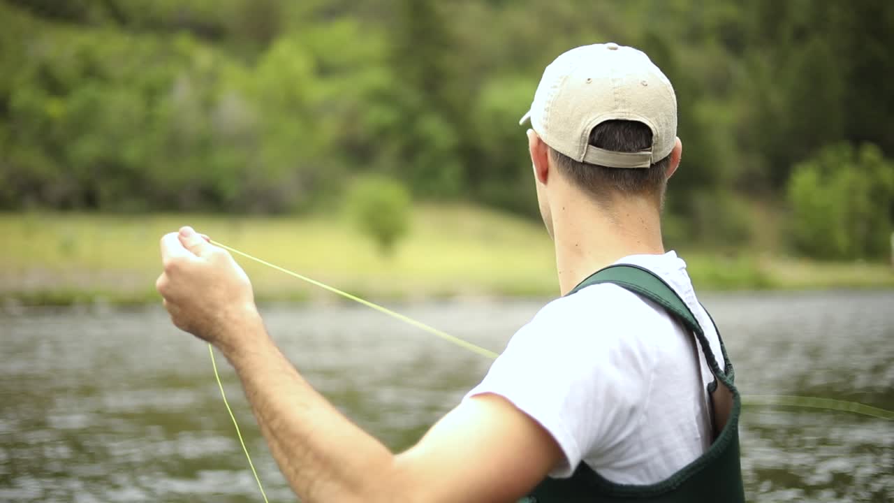 Rekaman Gerak Lambat seorang pria Kaukasia yang memancing lalat sambil berdiri di tengah Sungai Provo di Utah