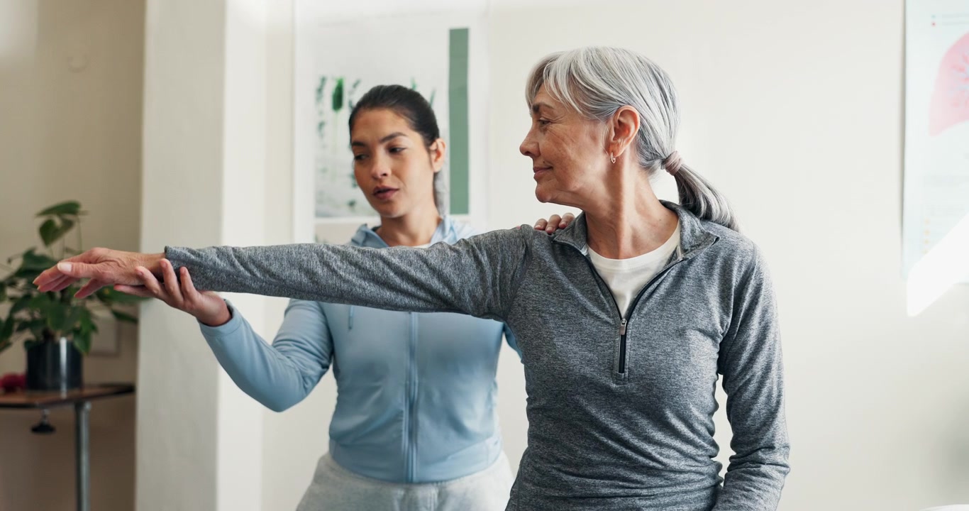 Physical Therapist Assisting Senior Woman with Arm Stretching Exercise