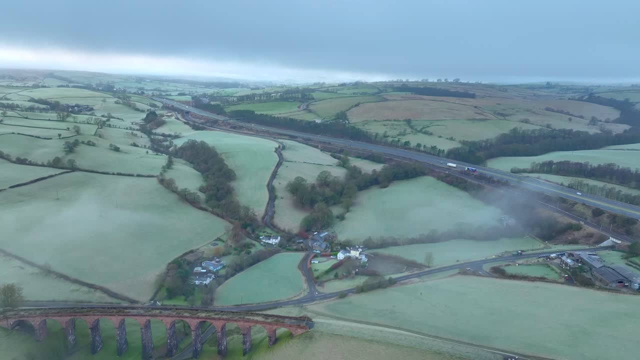 puente de viaducto de piedra abandonado y autopista m6 con tráfico ligero y niebla ligera y niebla al amanecer en invierno
