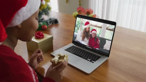 Mujer-Afroamericana-Con-Sombrero-De-Santa-Usando-Una-Computadora-Portátil-Para-Una-Videollamada-Navideña-Con-La-Familia-En-La-Pantalla