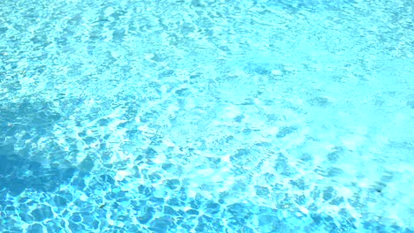 Textura-De-La-Superficie-Del-Agua,-Ondas-Y-Olas-De-Piscina-Limpia-En-Bucle-En-Cámara-Lenta,-Refracción-De-La-Luz-Solar-Vista-Superior-Textura-Arena-Blanca-Junto-Al-Mar,-Fondo-De-Bucle-De-Agua-Con-Brillo-Solar,