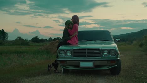couple hugging on a vintage car at sunset