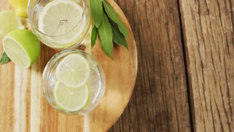 Video-of-glass-with-lemonade-and-lemons-on-wooden-board-and-wooden-surface