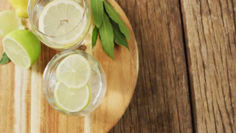 video de vidrio con limonada y limones en tablero de madera y superficie de madera
