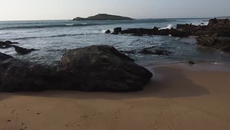 Flying-over-the-sand,-discovering-the-sea-and-a-iconic-island-at-sunset---drone-view