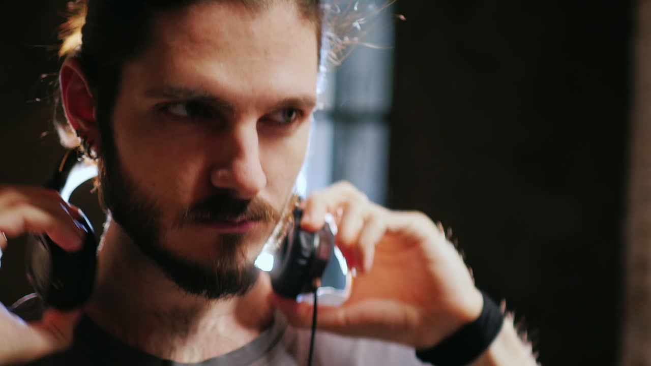 joven hipster con barba escuchando música alrededor de las paredes de ladrillo el viento susurra suavemente el