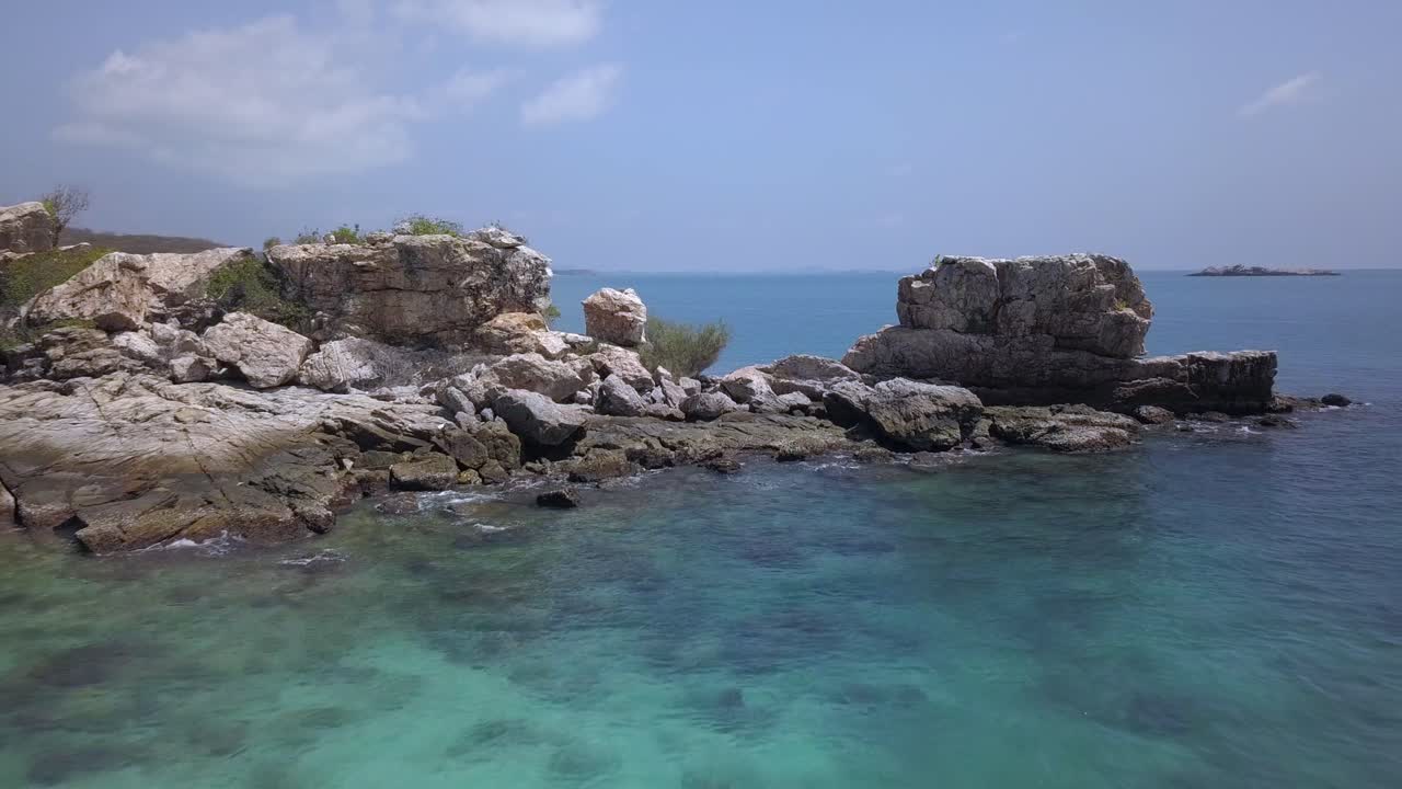 항공: 부분적으로 물에 잠긴 암석의 넓은 개구부를 통해 촬영한 저고도 돌리에서 저 멀리 아름다운 열대 섬을 드러냅니다.