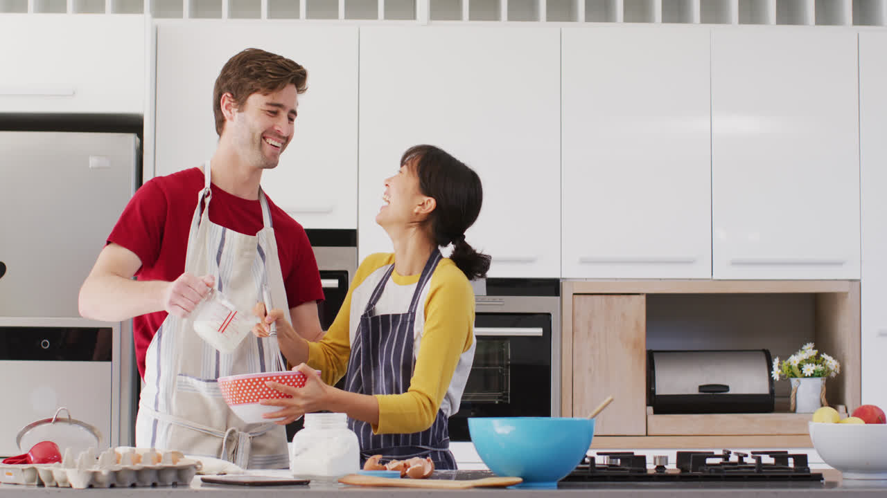 video de una pareja feliz y diversa horneando juntos en la cocina