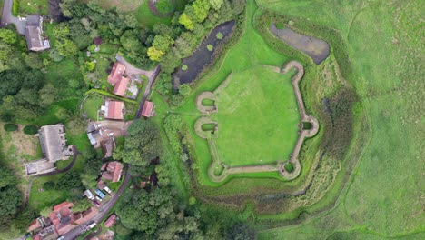 Aerial video footage of the remains of Bolingbroke Castle a 13th century hexagonal castle, birthplace of the future King Henry IV, with adjacent earthwork