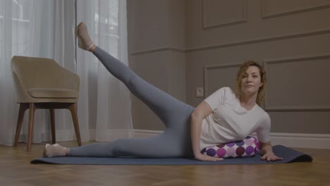 mujer caucásica en un tapete de yoga haciendo ejercicio en casa