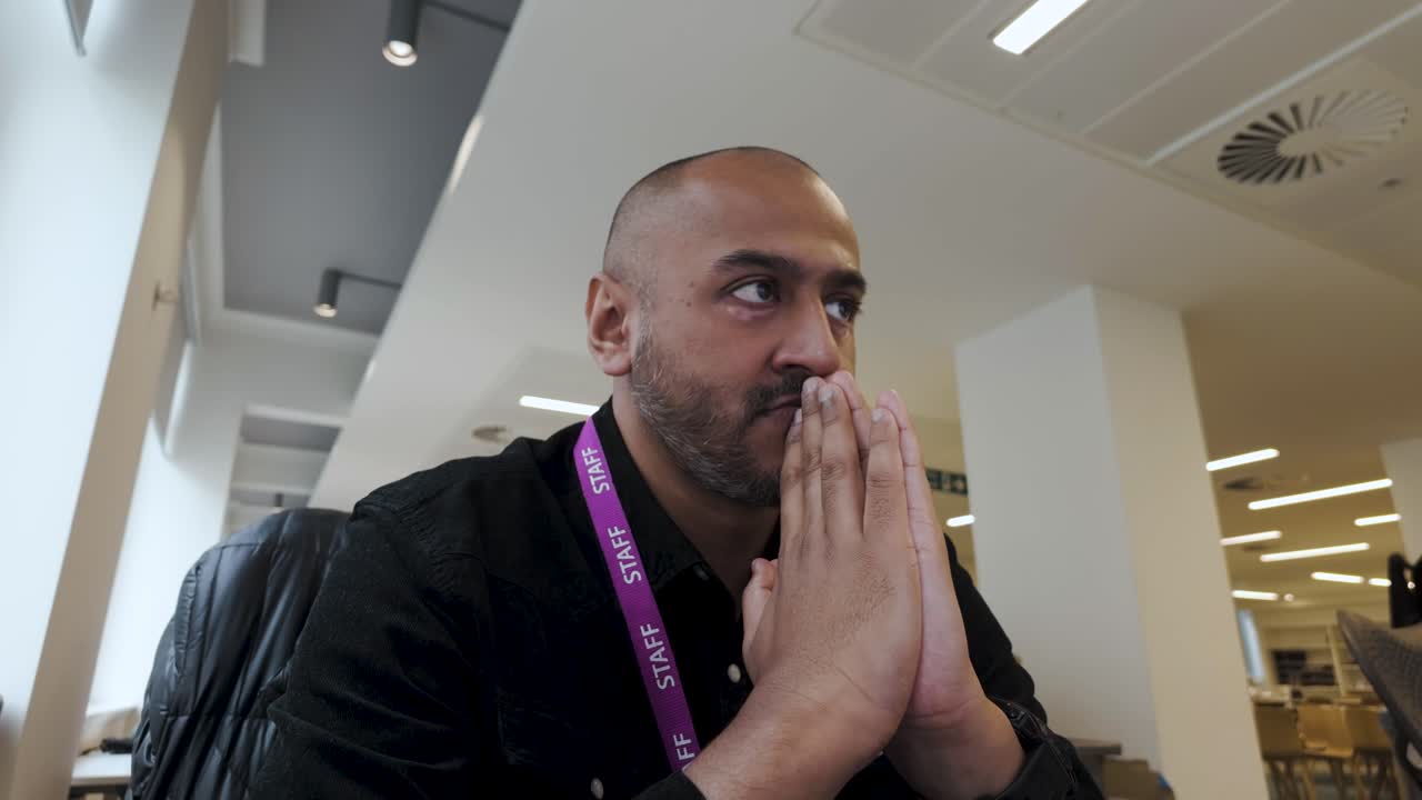 en un entorno de oficina interior, una persona está sentada, expresando una sensación de preocupación y tensión mientras imita el proceso de resolver una tarea o navegar emociones internas