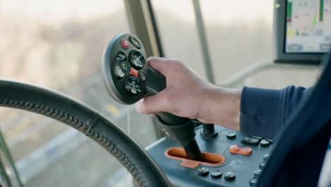 hand controlling joystick inside combine harvester cabin harvesting organic soybeans on sunny day