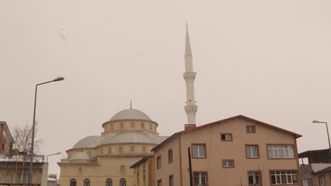viajes a turquía. erzurum, en turquía 02.05.2021 la nieve está cayendo sobre la mezquita, nevada. clima frío -8 grados centígrados, temporada de invierno. congelación, helada, hielo, congelación, hielo.