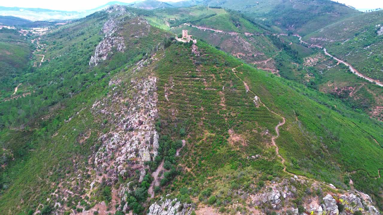 vista aérea de un paisaje verde escarpado y una pequeña torre, 4k
