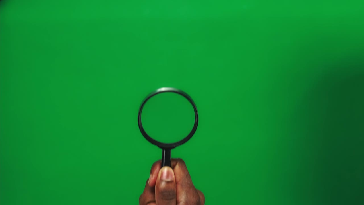 3 manos de hombre negro están sosteniendo una lupa y moviéndola en un fondo de pantalla verde