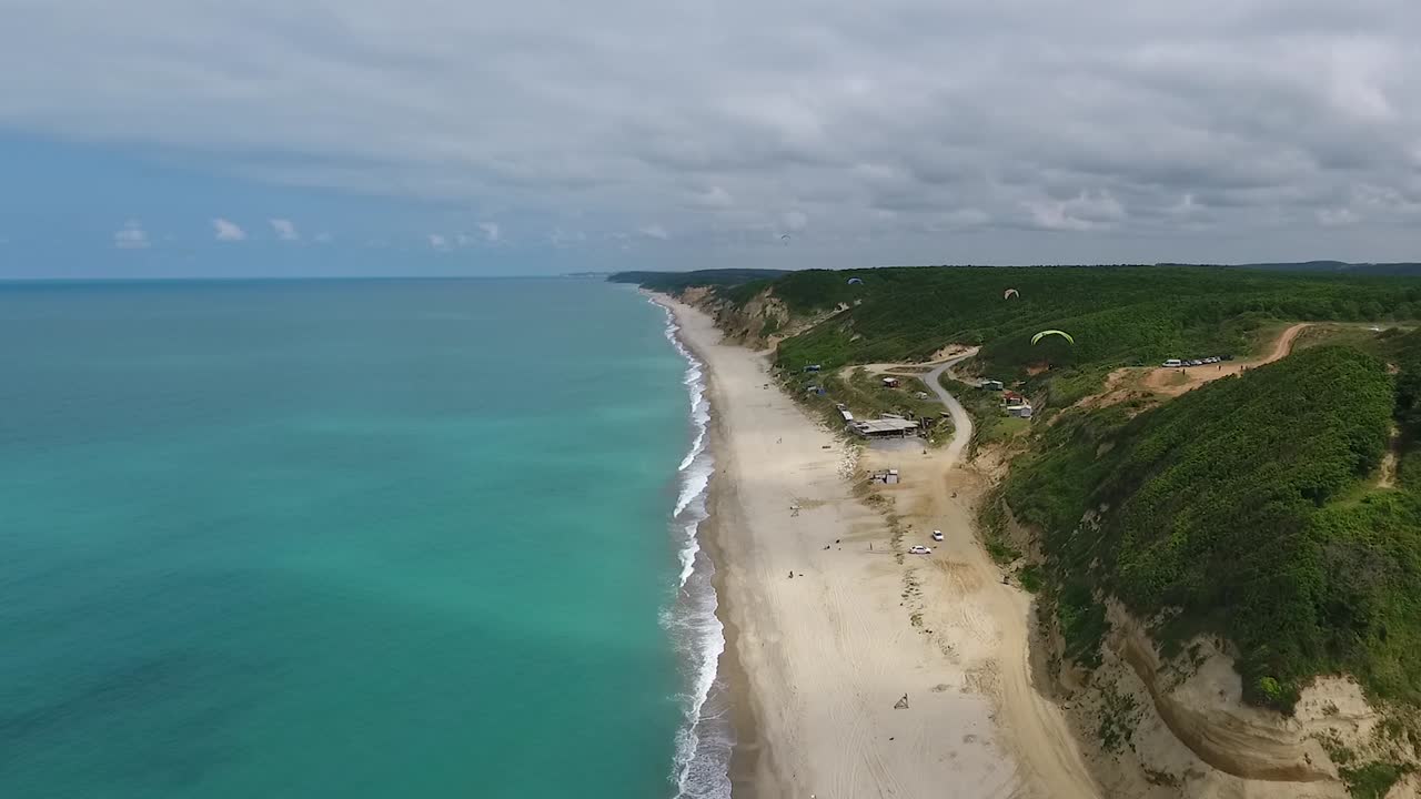 parapentes sobrevolando la playa y las colinas verdes persecución de drones