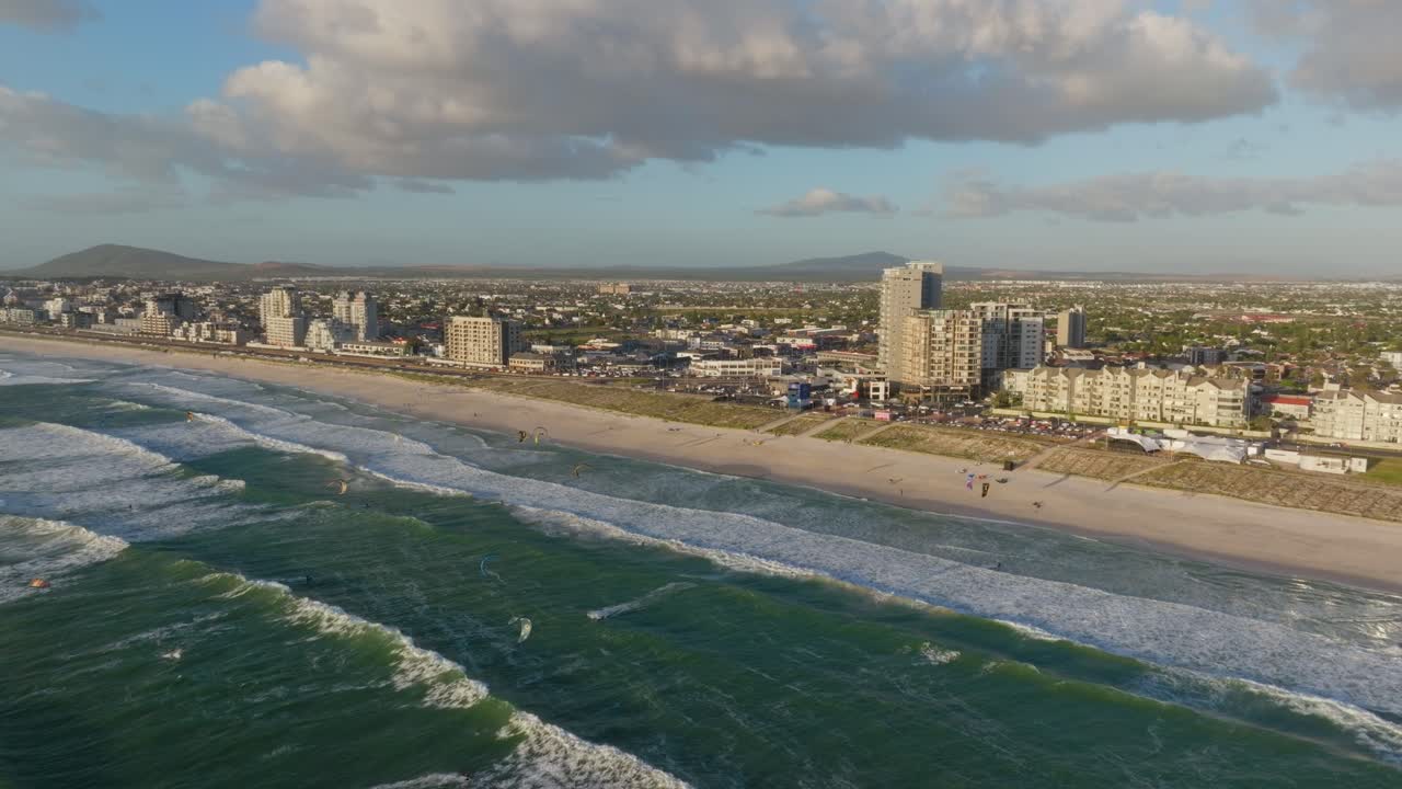 Ocean waves roll toward Blouberg's shore with urban village in the backdrop