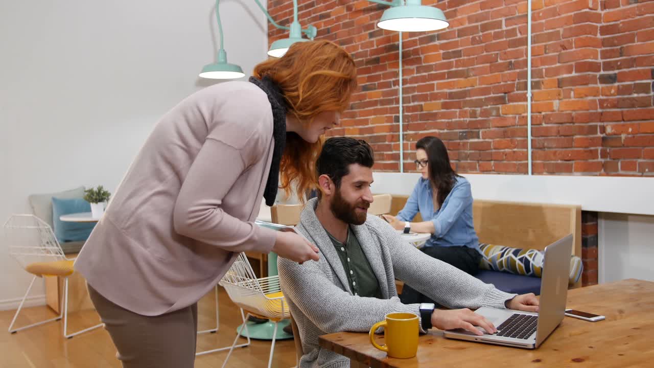 Business executives discussing over laptop