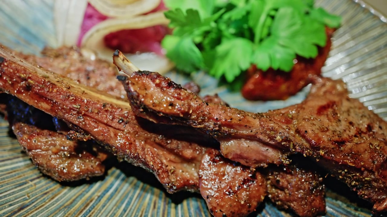 Hidangan daging panggang yang disajikan di atas piring dekoratif, dihiasi dengan rempah-rempah segar dan sayuran.