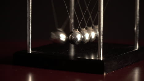Newton's-cradle-over-black-background,-view-from-one-side-SLOW-MOTION