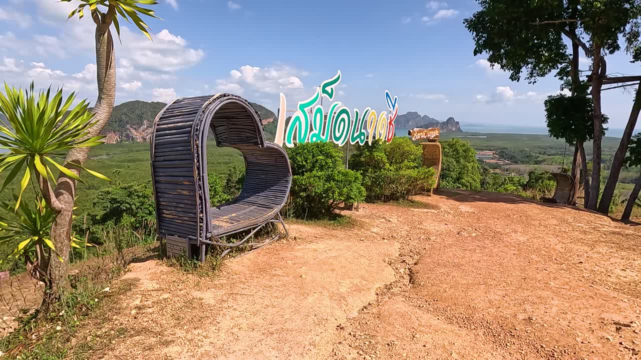 Panoramic view of Phang Nga Bay from a hilltop in Phuket, featuring a heart-shaped bench under clear skies
