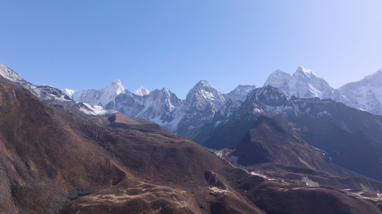 Glidende luftdronebillede af Himalaya-landskabet i Nepals Khumbu-region langs ruten til Everest Base Camp. Sneklædt bjergkæde med Ama Dablam og tårnhøje 8000-meter tinder