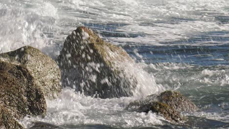 ocean wave breaking over rocks in white spray, mediterranean, spain