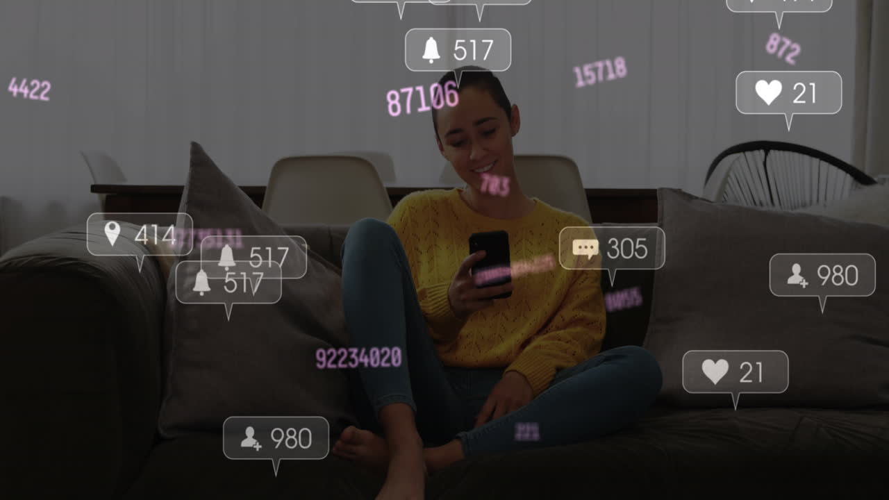 animación de iconos de las redes sociales sobre una mujer biracial sonriendo mientras usa un teléfono inteligente en casa