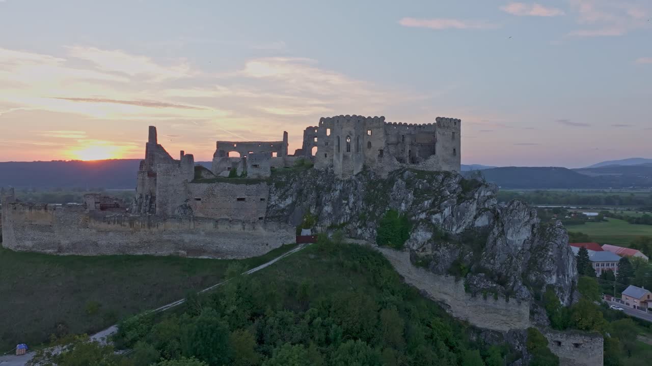 Prospettiva drone del Castello di Beckov che risplende contro il cielo serale.