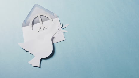 primer plano de paloma blanca con hoja, signo de paz blanco, sobre y espacio de copia sobre fondo azul