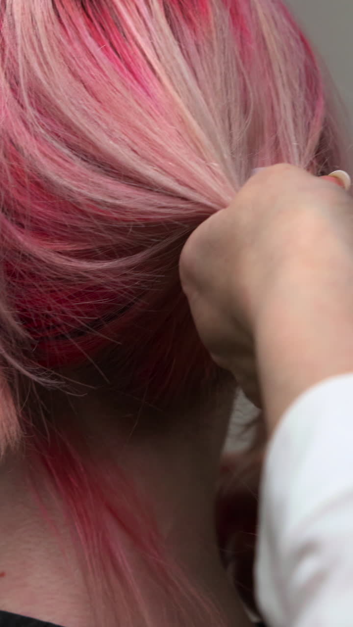 Primer Plano de Mano Peinando Cabello Rosa Vibrante y Rubio