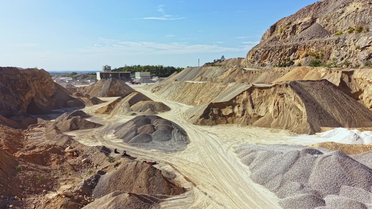 Industrial site with large piles of gravel and sand during daylight in a quarry setting