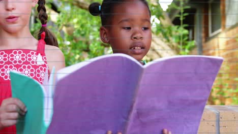 animation of school icons over schoolgirls reading at school