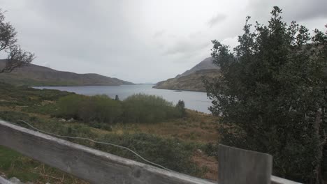 Disparo-Pasando-Por-Encima-De-Una-Valla-Mirando-Un-Lago-En-Las-Tierras-Altas-De-Irlanda-Con-Montañas-Y-árboles