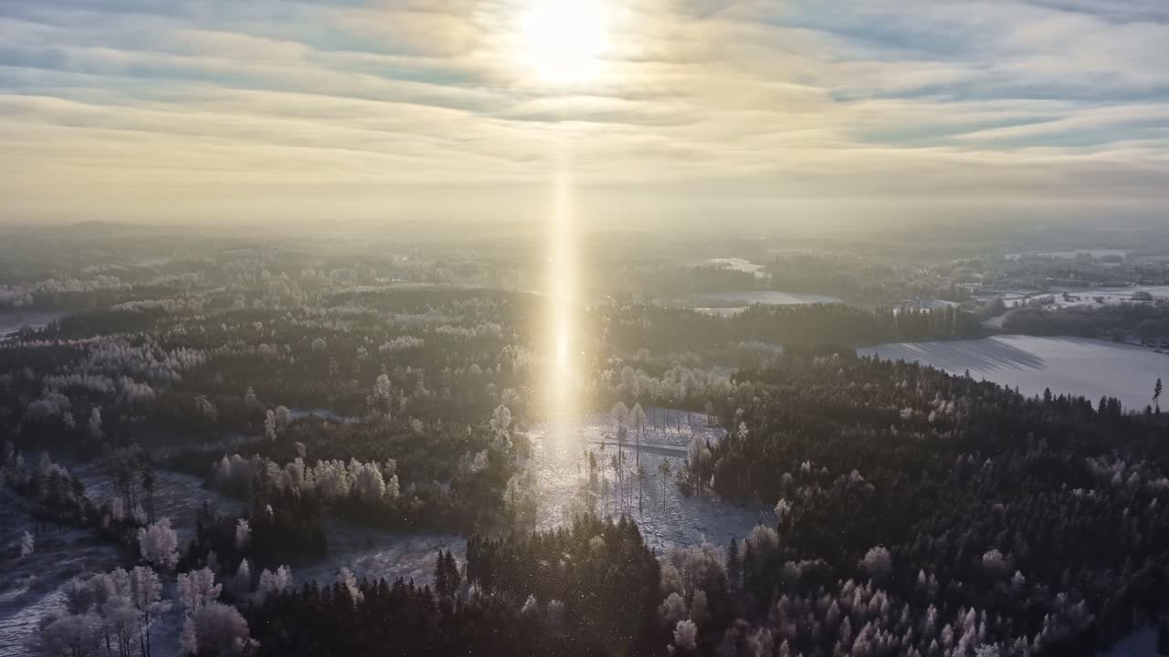 Raggio di sole che illumina una foresta invernale e laghi ghiacciati all'alba, il sole che rischiara alberi brinati e laghi ghiacciati, vista aerea