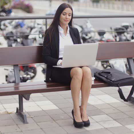 mujer sentada con laptop frente a motocicletas