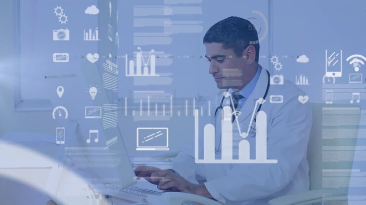Male doctor sitting at desk typing on laptop in medical office, showcasing floating health charts