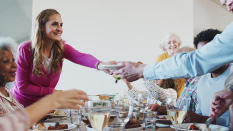 multi-generation family enjoying meal sitting around table at home together