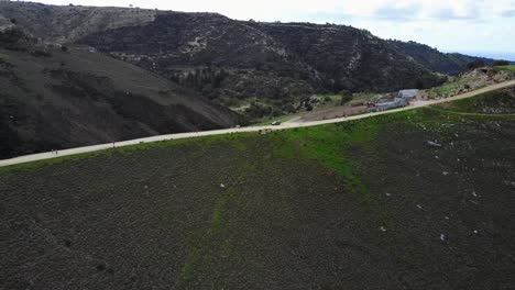 amplia vista aérea de los corredores que trotan en un camino en la ladera de la montaña en akamas en chipre paphos con exuberantes colinas verdes