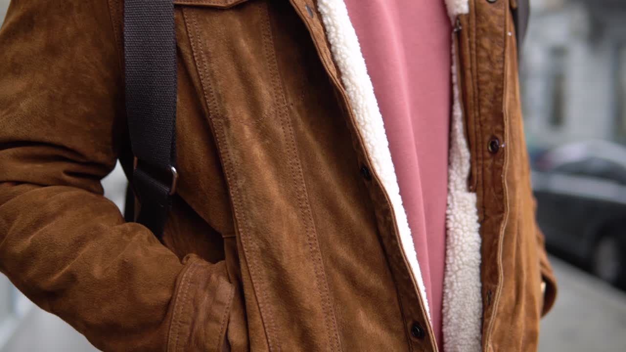 A man with shoulder backpack stands outdoor near the office center