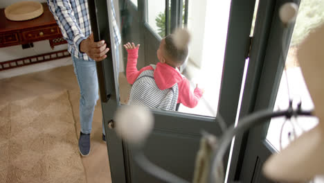 african american father saying goodbay to son, house for school, slow motion