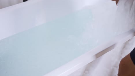 man filling bath with ice cubes, close up