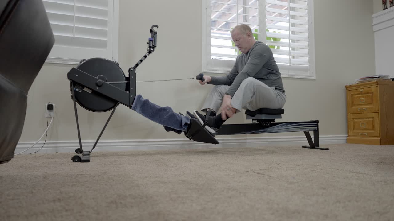 Senior man finishes his workout on a rowing machine